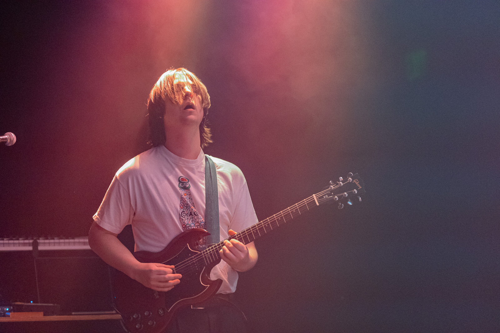 Man playing electric guitar, surrounded by smoke and lights
